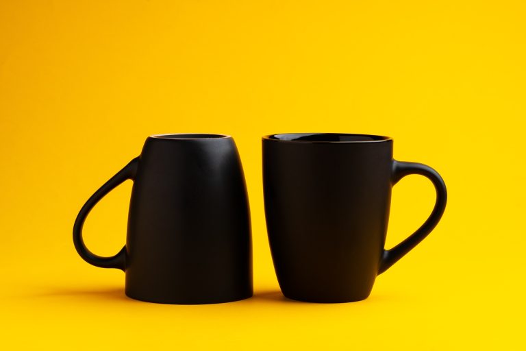 Two mugs on yellow studio background close up